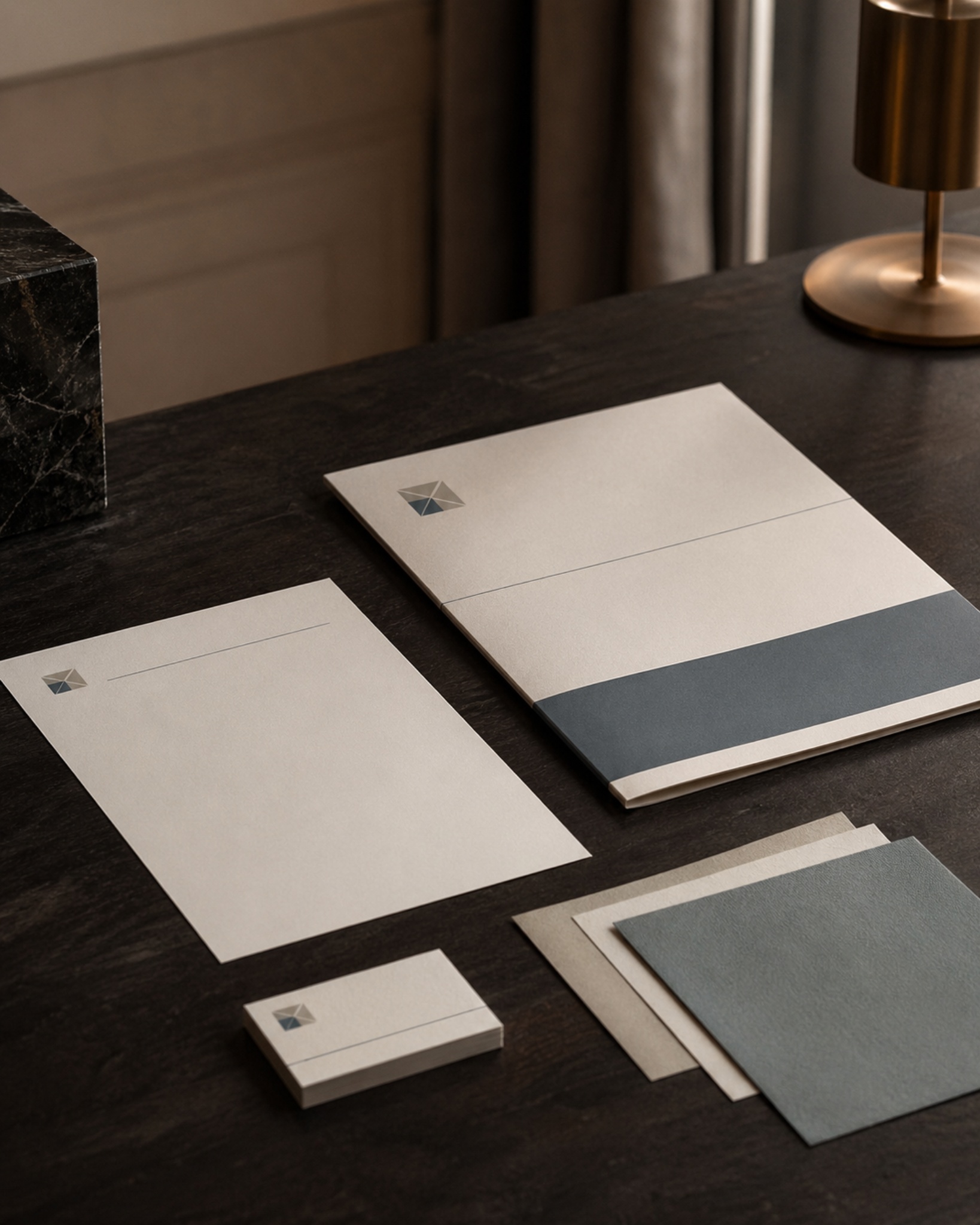 Editorial still life of refined business identity materials on a dark wood desk.