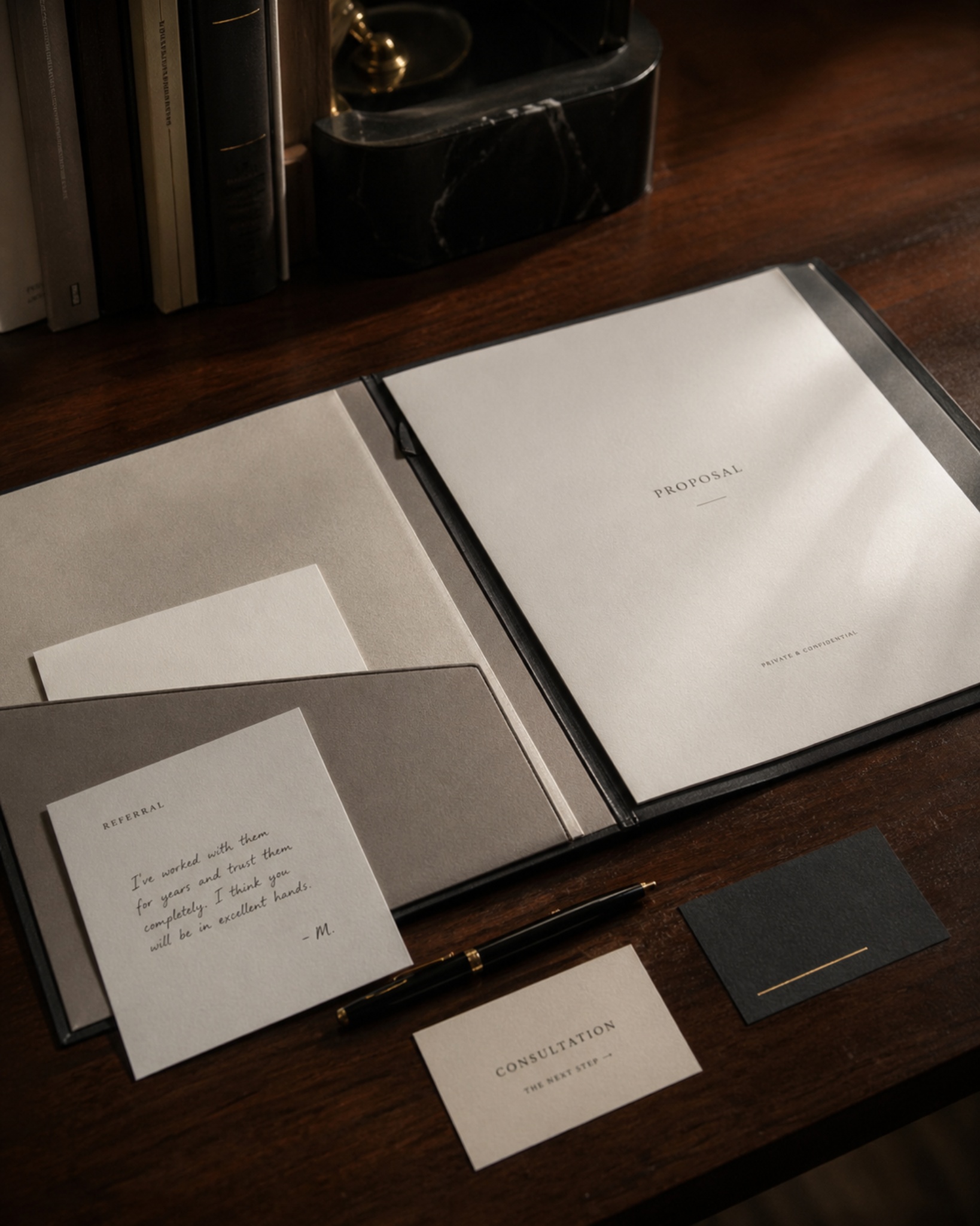 Open proposal folder, referral note, consultation card, and pen on a professional desk.